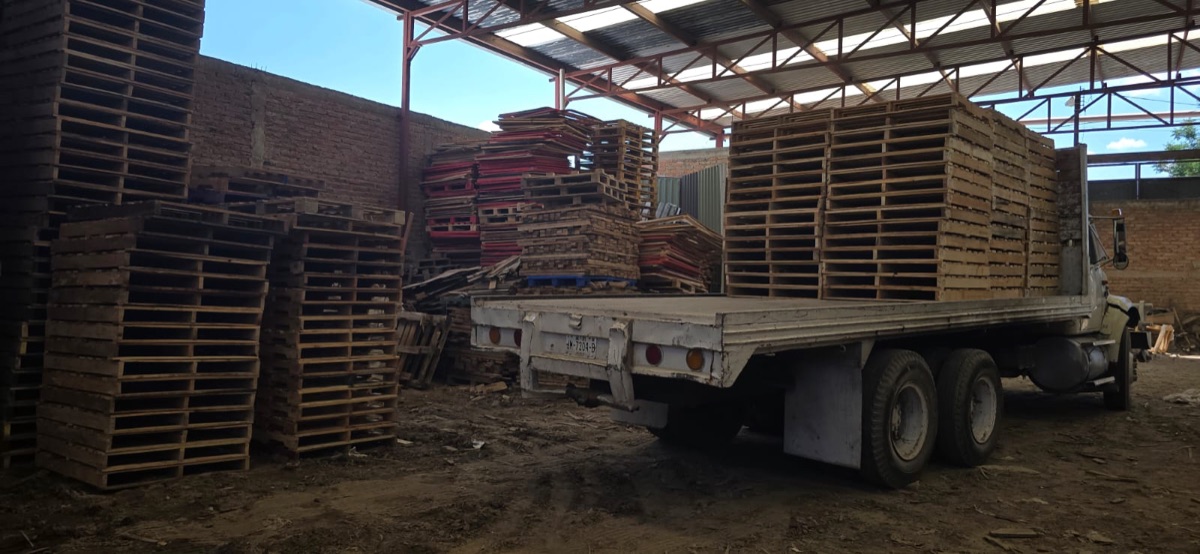 Camión flatbed cargando tarimas para entrega al corredor industrial de El Salto